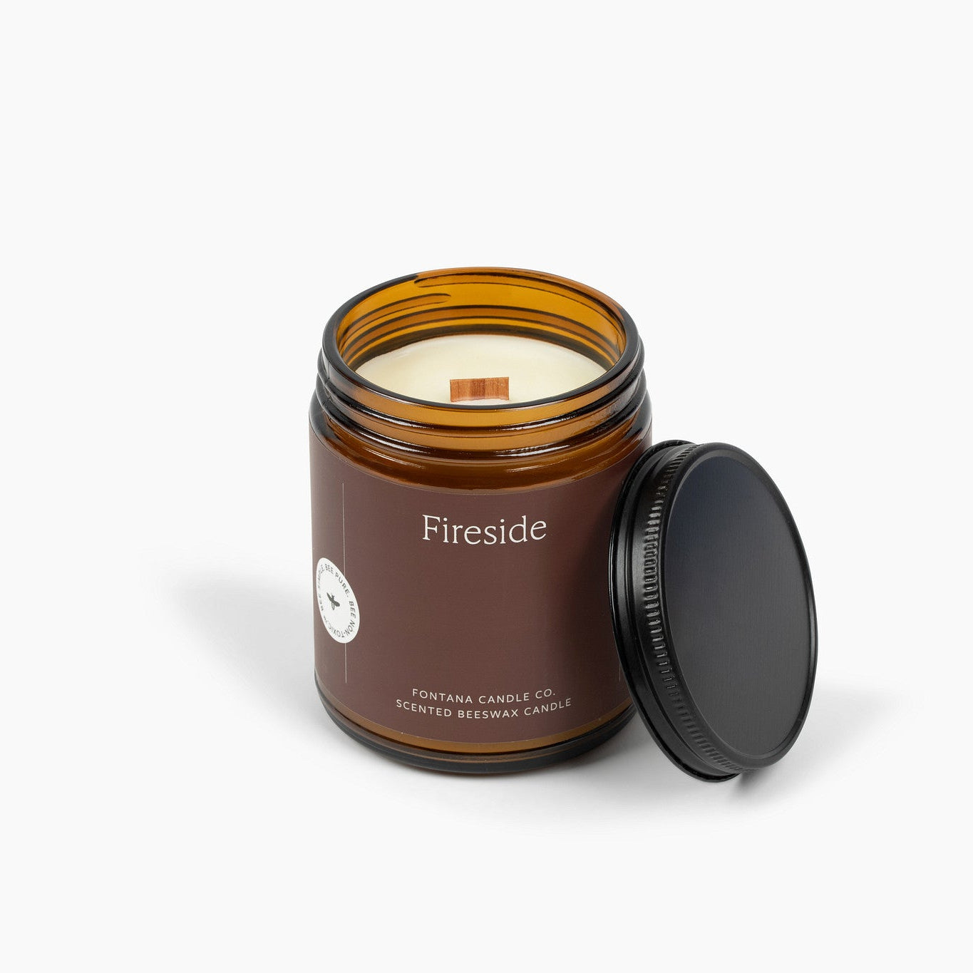 Fireside candle in an amber jar with a black lid on a white background