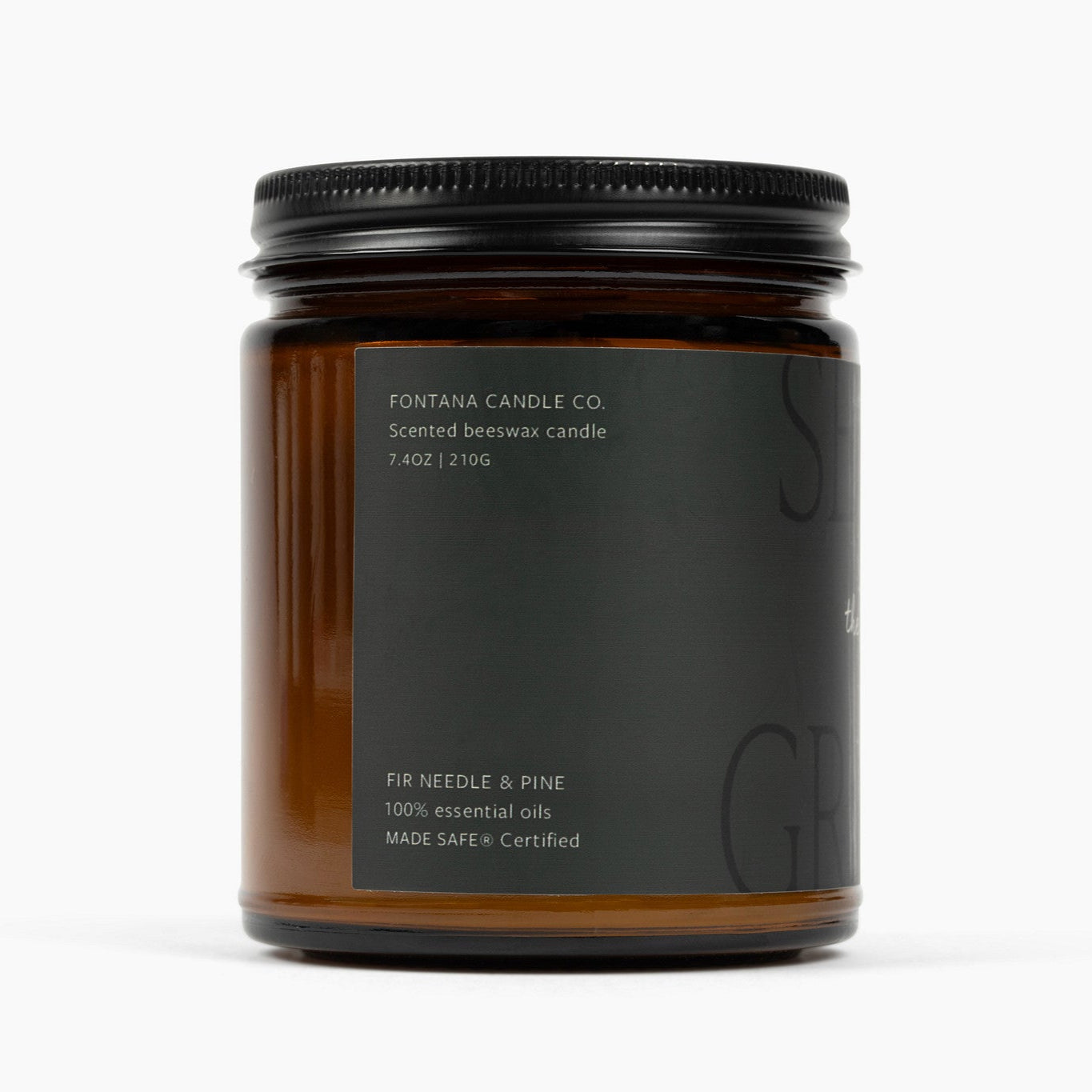 Side of amber glass jar candle with a dark green label and the scent: Fir Needle & Pine.