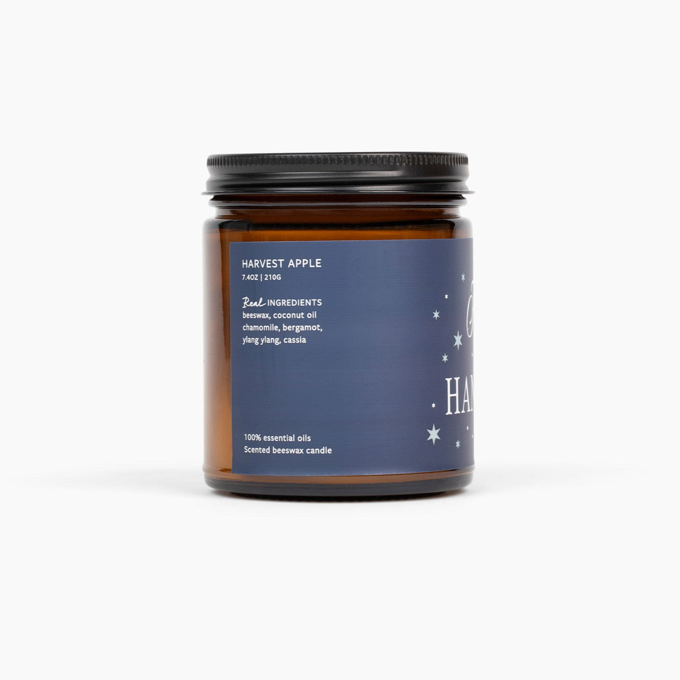 Side view of an amber glass jar candle with a blue label, and the scent name Harvest Apple/