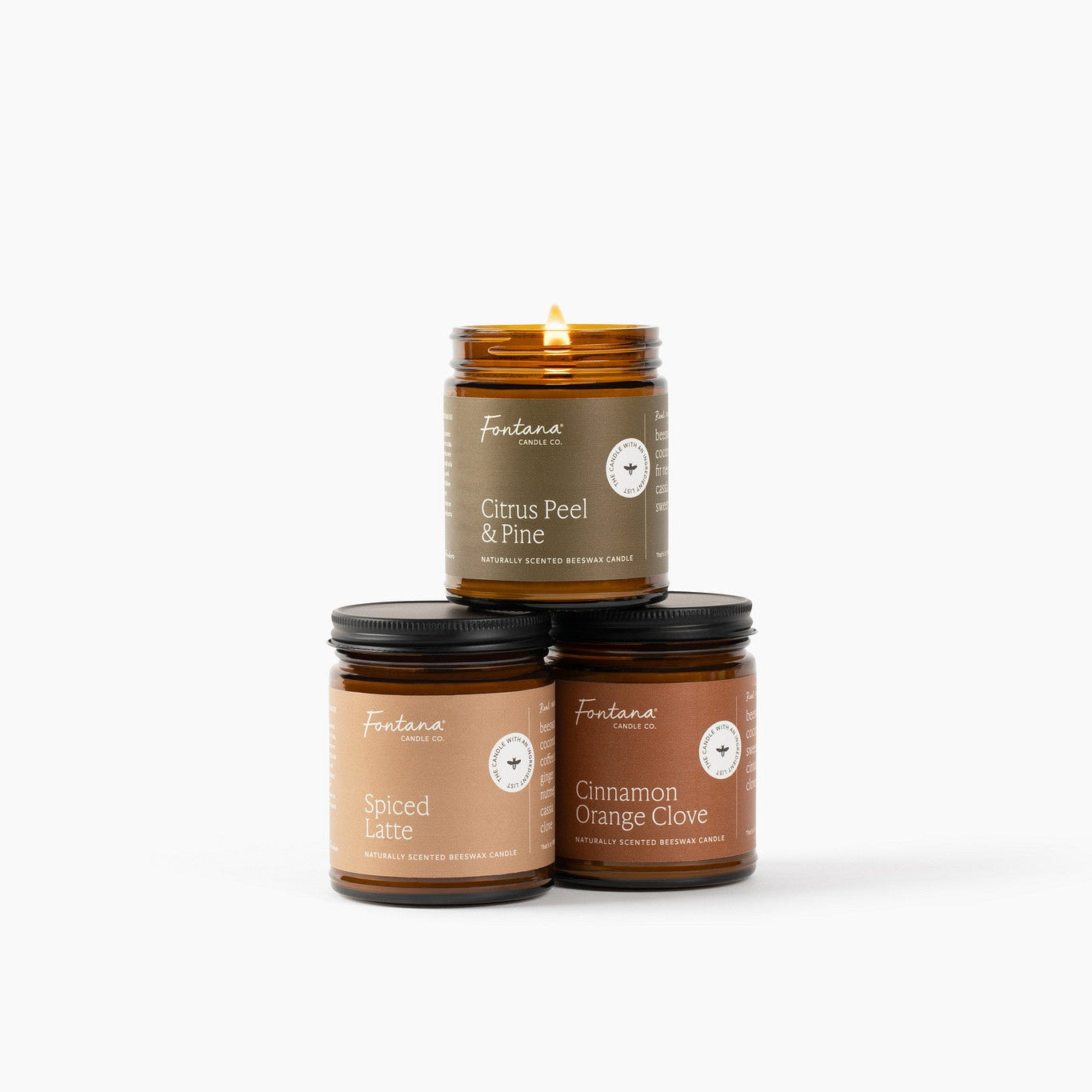 Three candles stacked on a white background with labels Citrus Peel &amp; Pine, Spiced Latte and Cinnamon Orange Clove.