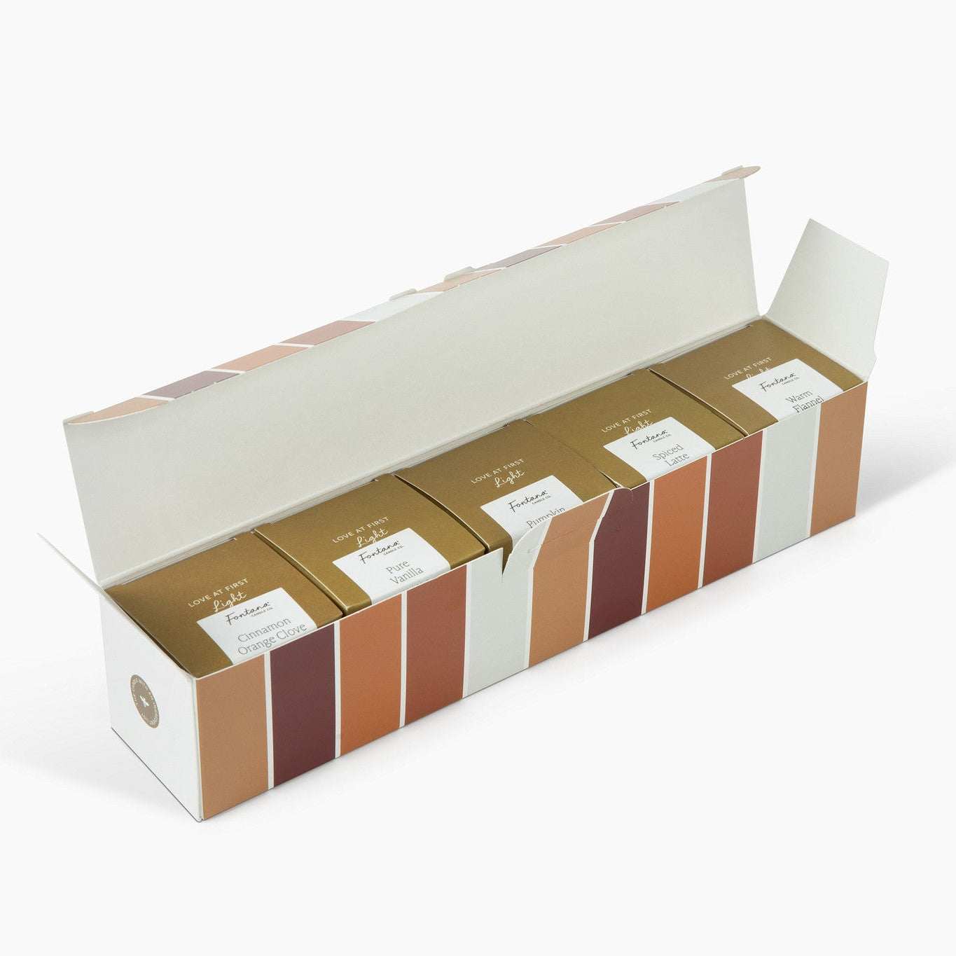 An open long cardboard box displaying five boxed candles, Cinnamon Orange Clove, Pure Vanilla, Pumpkin Pie, Spiced latte and warm Flannel on a clean white background.