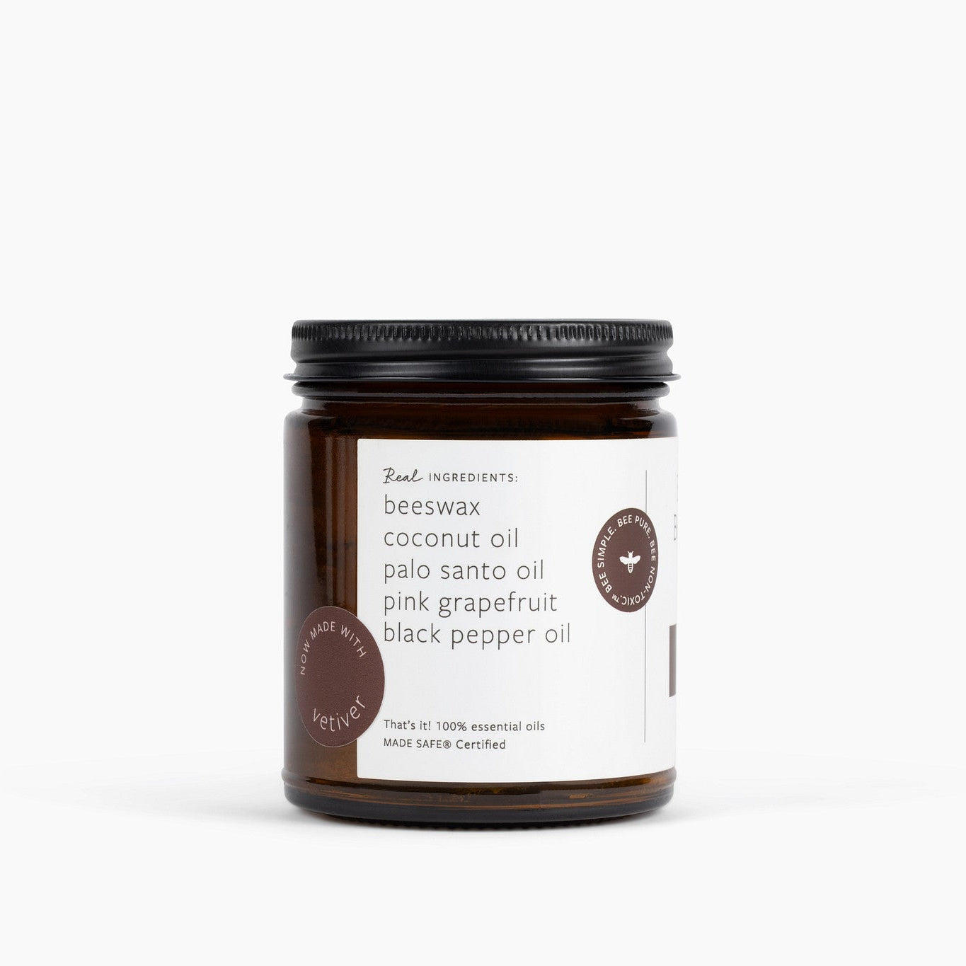 An amber glass jar candle with a black metal lid and a white label, photographed on a clean white background. The label reads 'Real Ingredients' and lists ingredients including beeswax, coconut oil, palo santo oil, pink grapefruit oil, black pepper oil and vetiver.