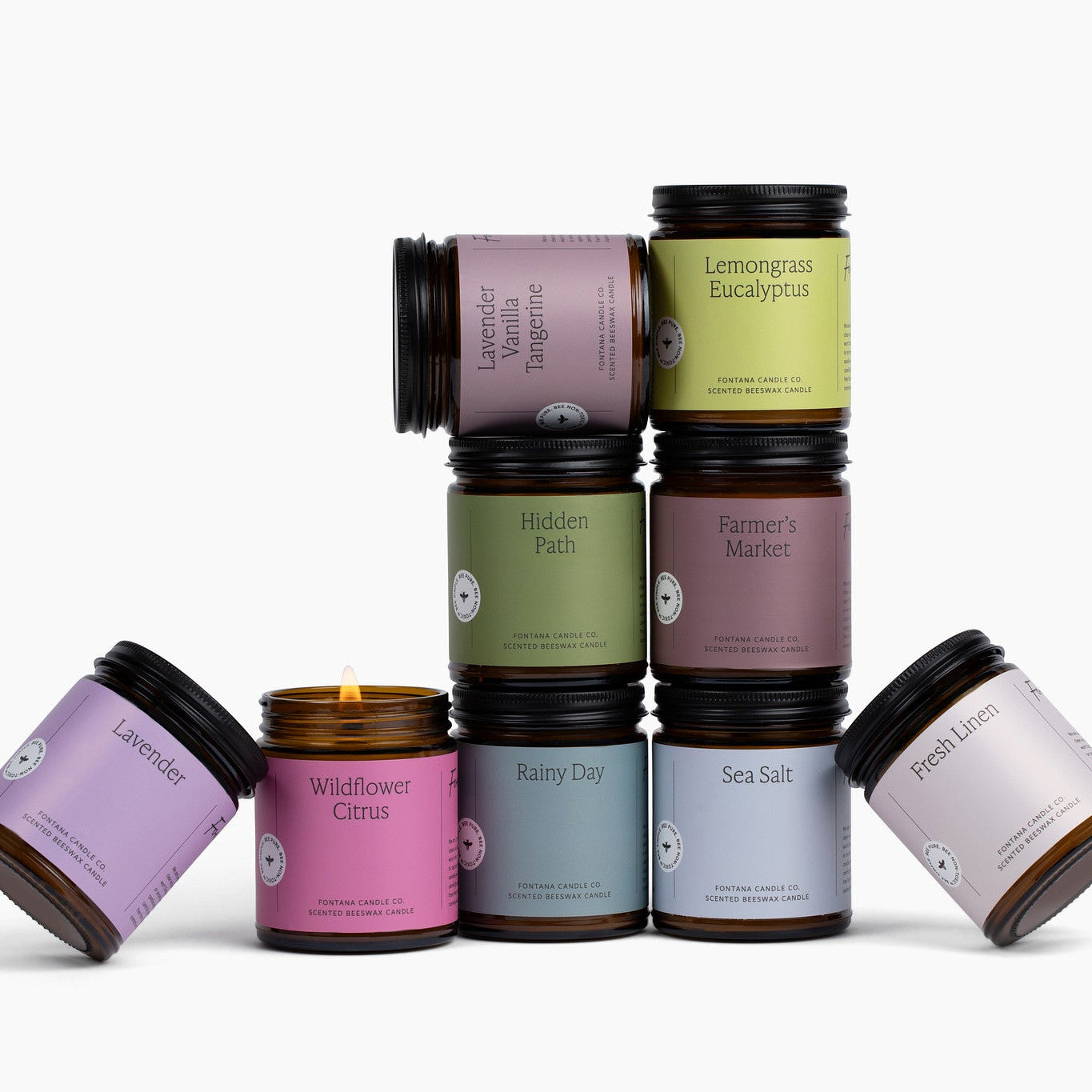 9 amber glass jar candles with colorful labels in front of a white background.