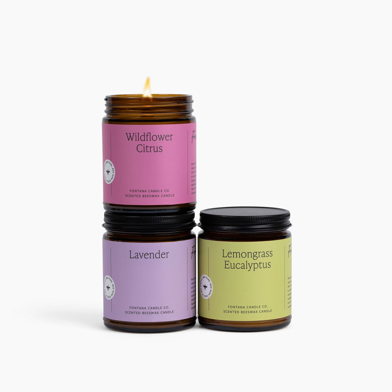 Three bright spring amber glass jar candles with different scents on a white background.