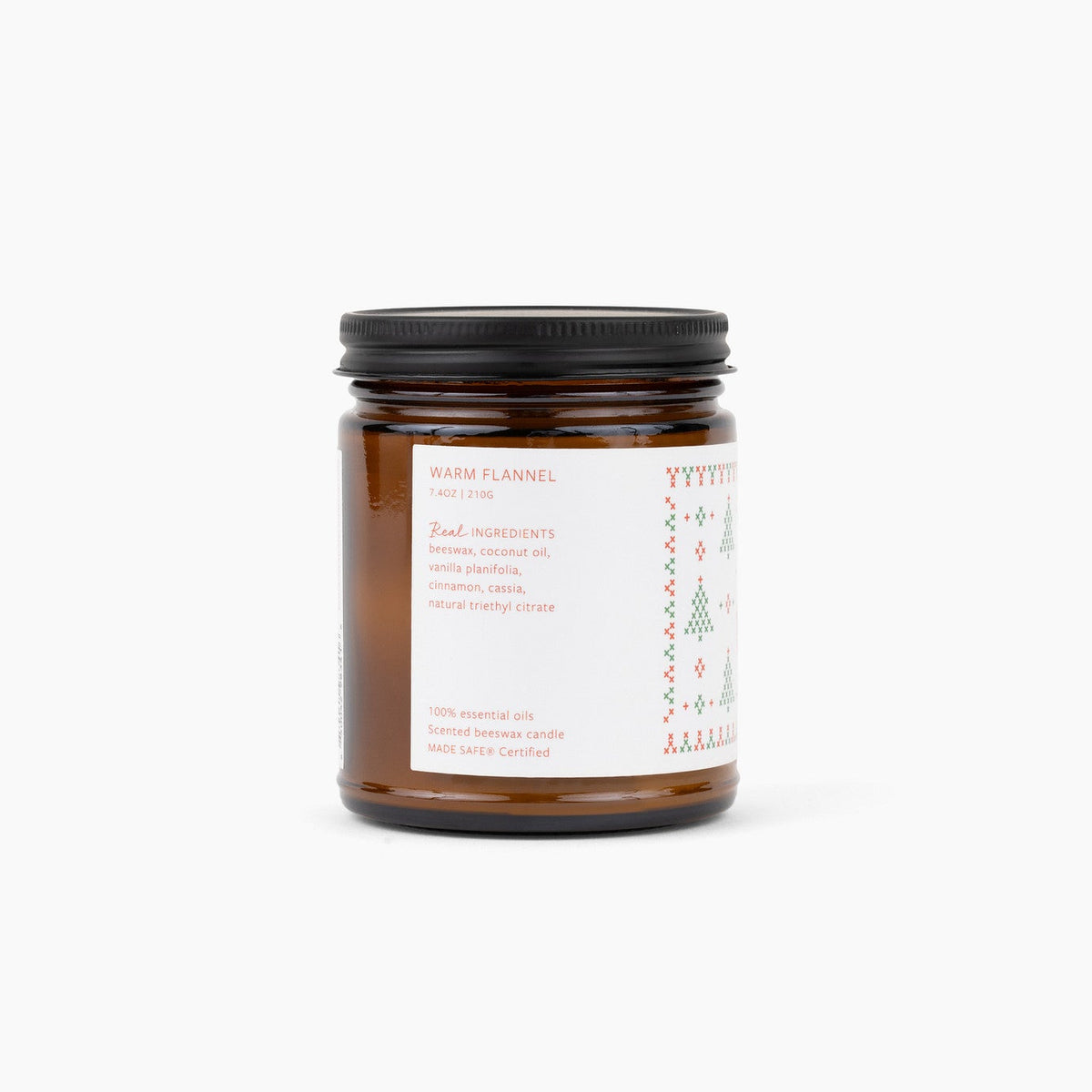 A single amber glass jar candle with a black metal lid and a white label, photographed on a clean white background.