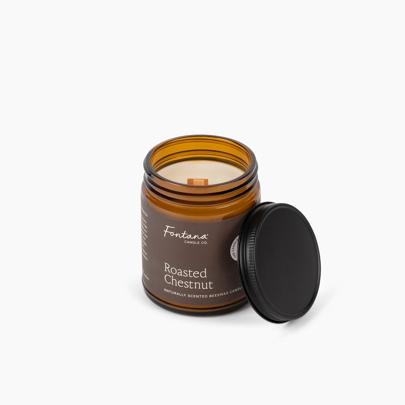 Candle in a glass jar with a wooden wick labeled 'Roasted Chestnut’ on a white background.