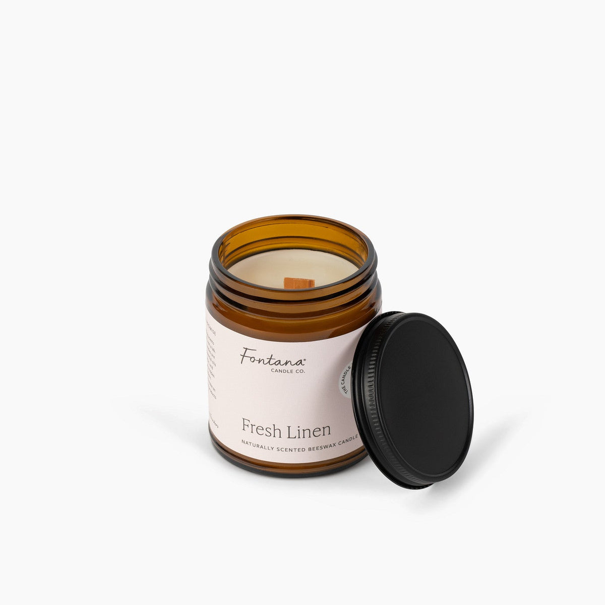 elevated view of the fresh linen 9oz jar candle, with the untreated wooden wick showing