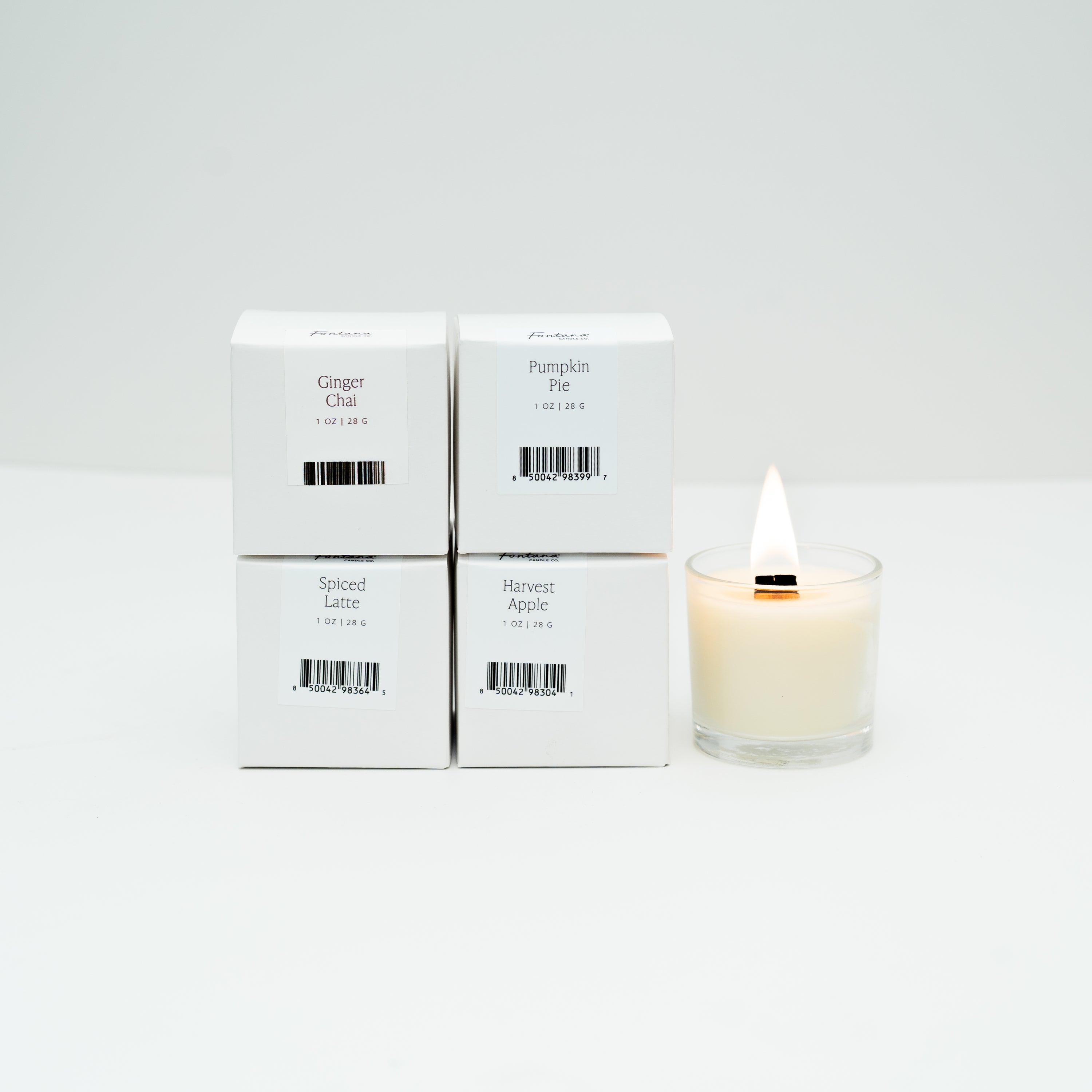 Four boxes of Mini candles next to one lit mini glass votive candle, on a white background.
