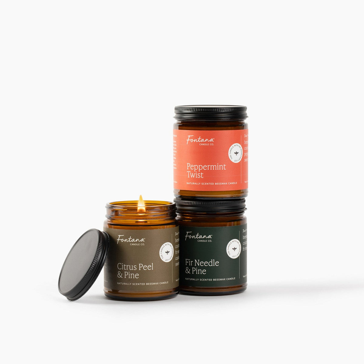 Three candles with different scents Citrus Peel &amp; Pine, Peppermint Twist and Fir Needle &amp; Pine on a white background