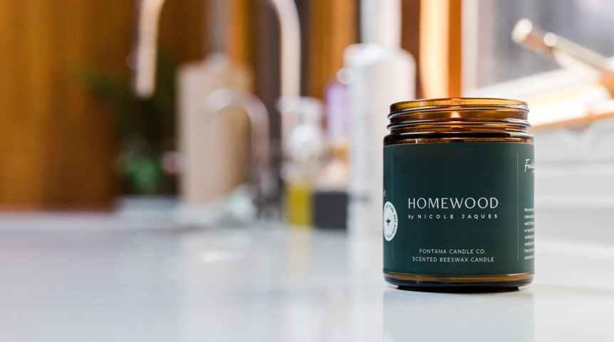 Homewood candle jar sitting on a kitchen counter with a blurred background.
