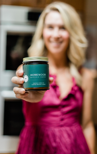 Nicole Jaques holding a jar of Homewood candles in a kitchen setting