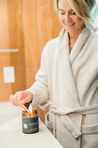 Nicole Jaques in a robe lighting a Homewood candle in her bathroom.