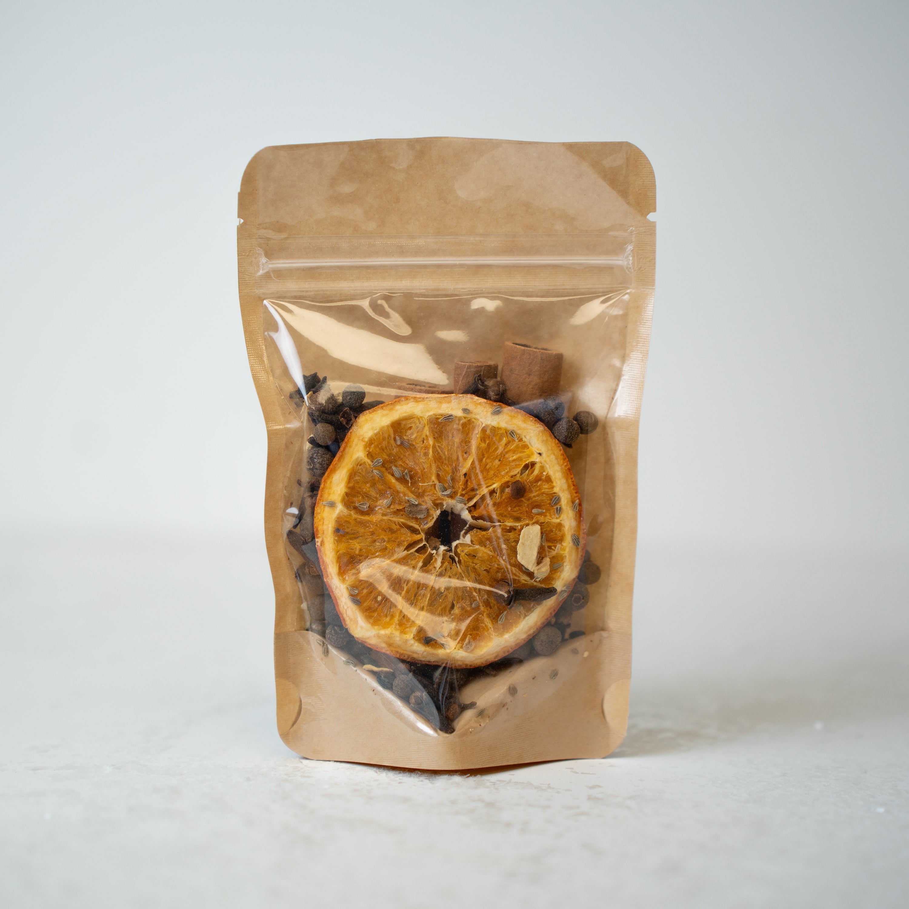 Brown paper packaging with dried orange slices and herbs on a white background