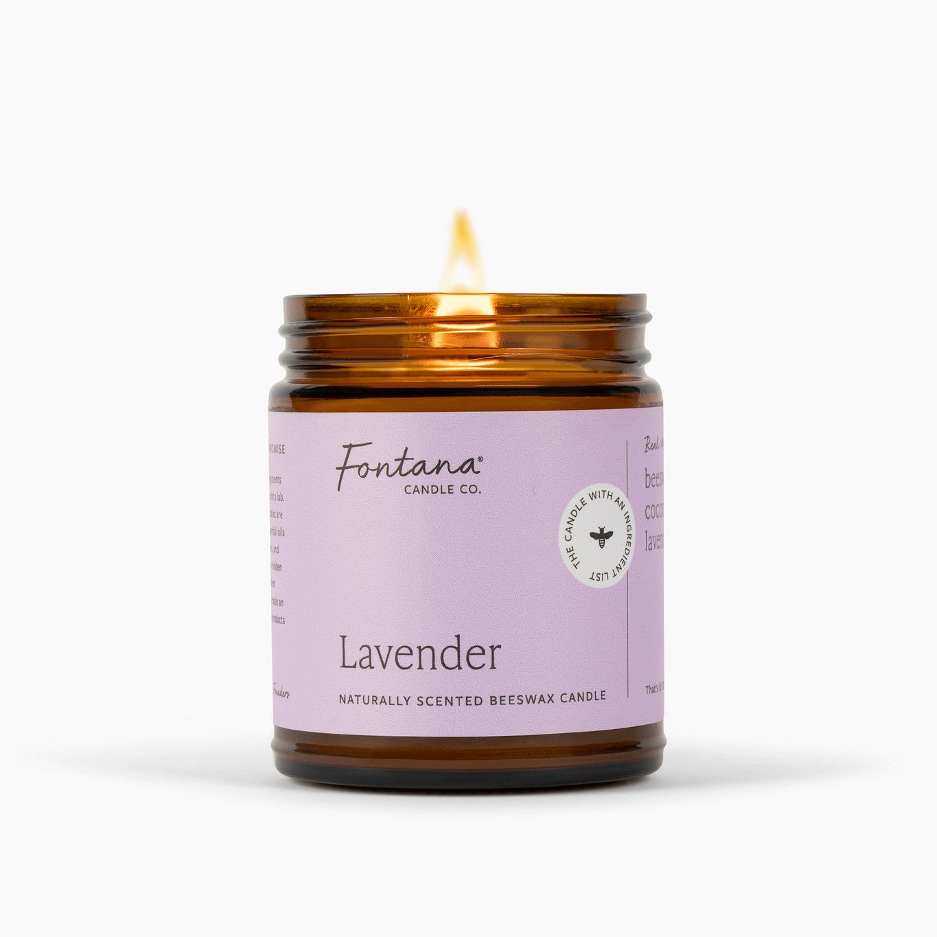 Lit amber glass jar candle with a purple label, on a white background.