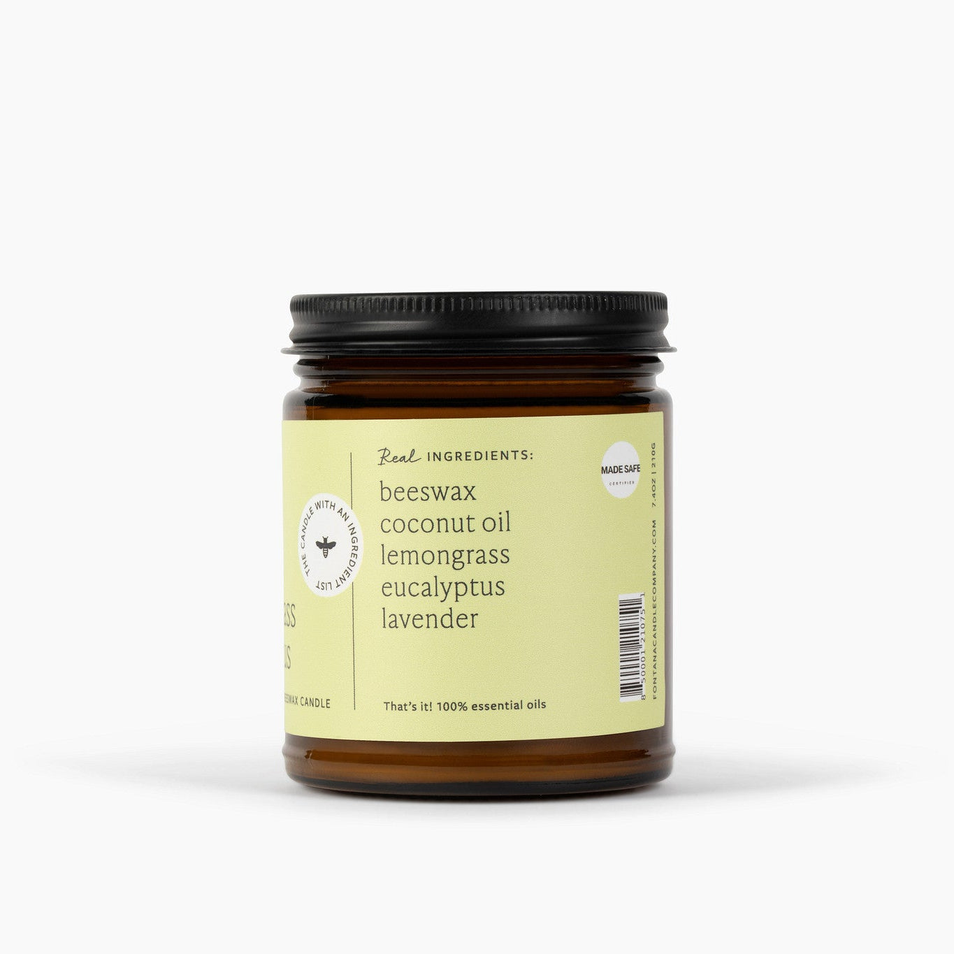 Side view of an amber glass jar candle with a black lid, light green/yellow label. The candle is in front of a white background. 