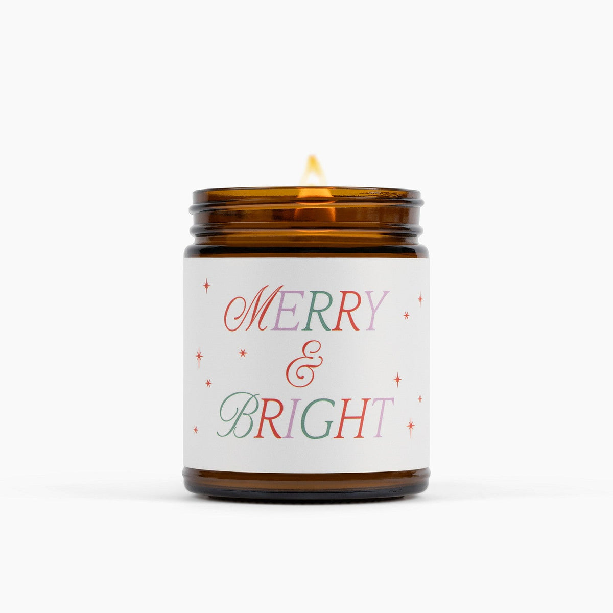 Candle in a brown glass jar with a 'Merry &amp; Bright' label on a white background