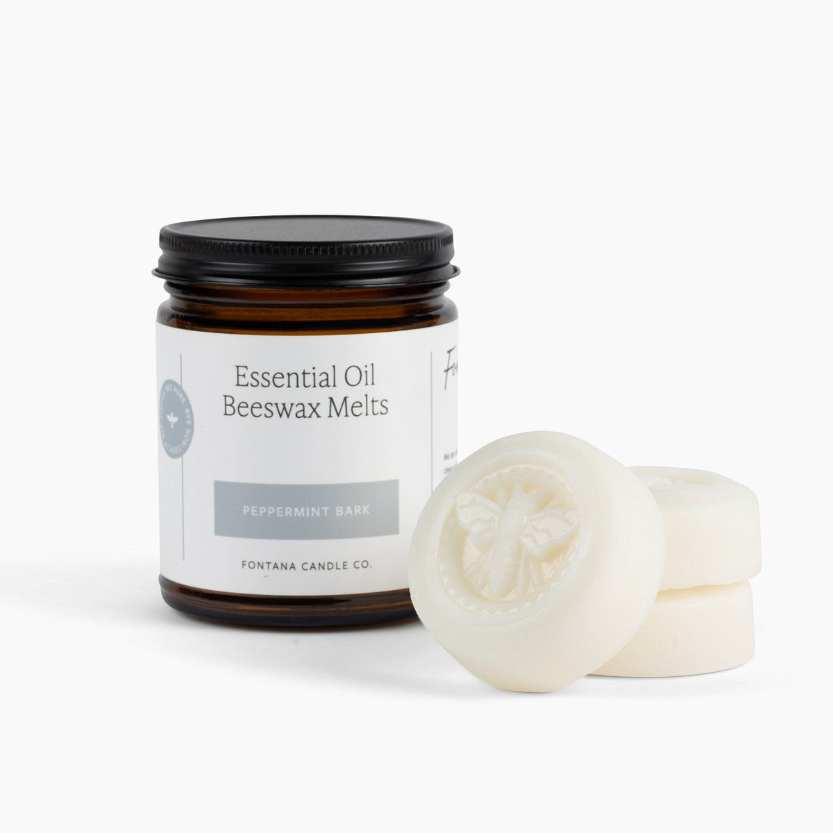 Jar of essential oil beeswax melts with a few melts on a white background