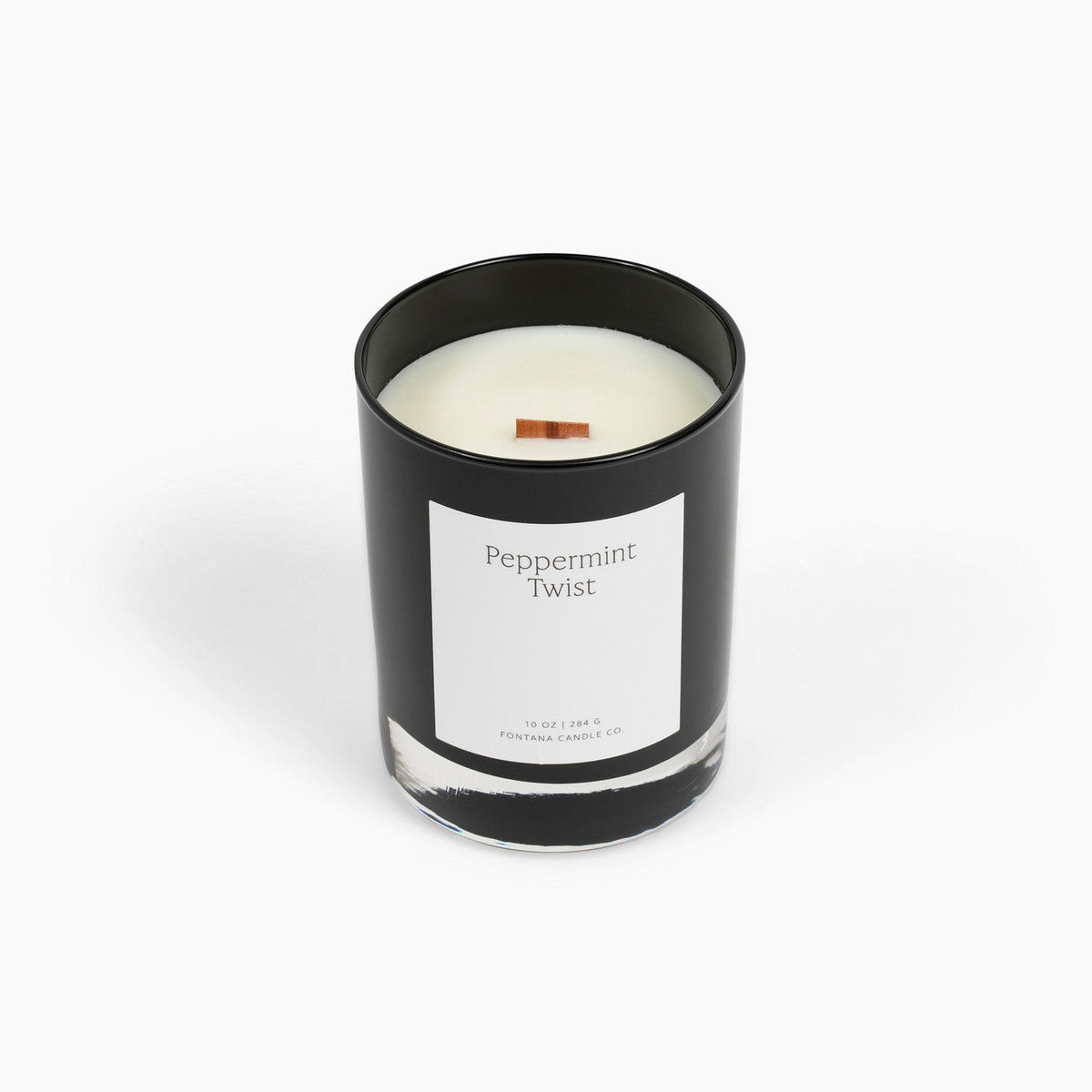 A black glass jar Noir candle with a white label reading 'Peppermint Twist' and a wooden wick, centered on a clean white background.
