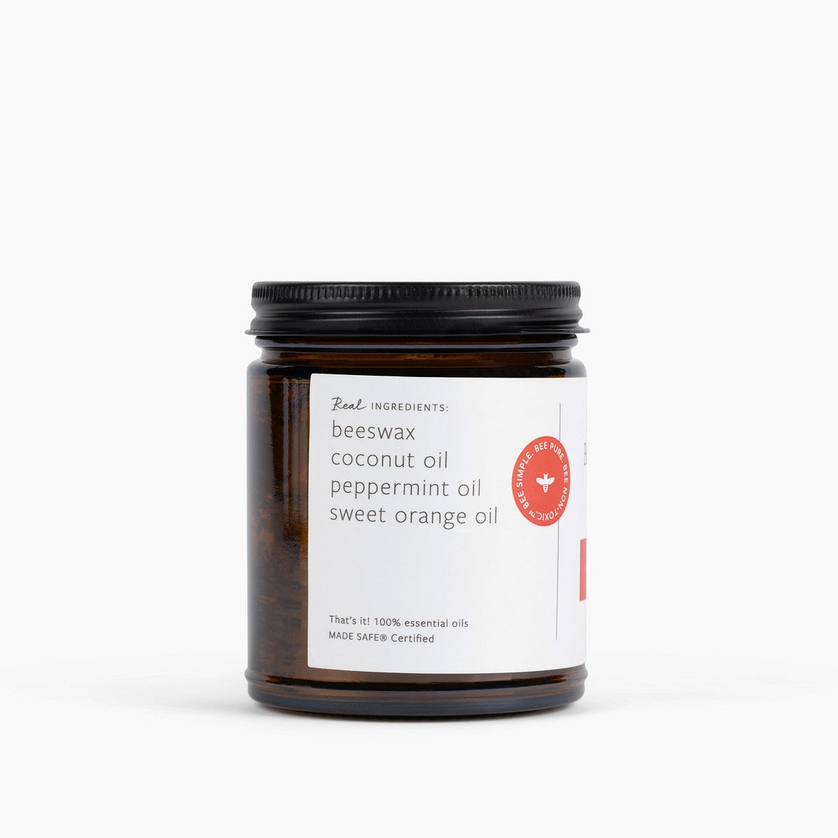 An amber glass jar candle with a black metal lid and a white label, photographed on a clean white background. The label reads 'Real Ingredients' and lists ingredients including beeswax, coconut oil, peppermint oil and sweet orange oil.
