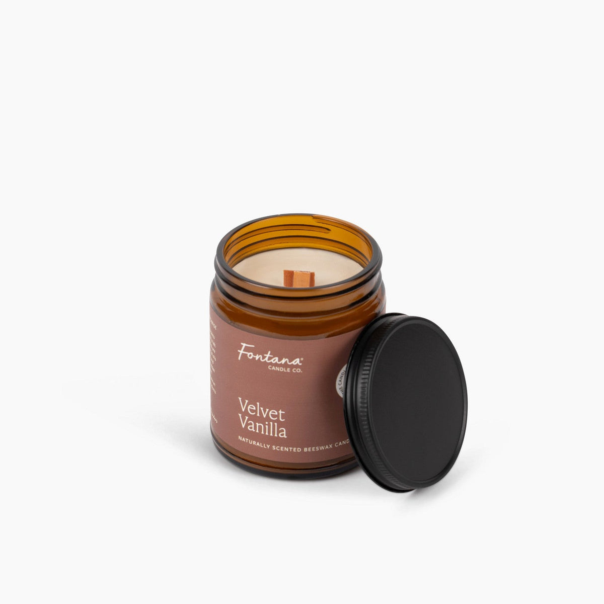 Candle in a glass jar with a wooden wick labeled 'Velvet Vanilla’ on a white background.