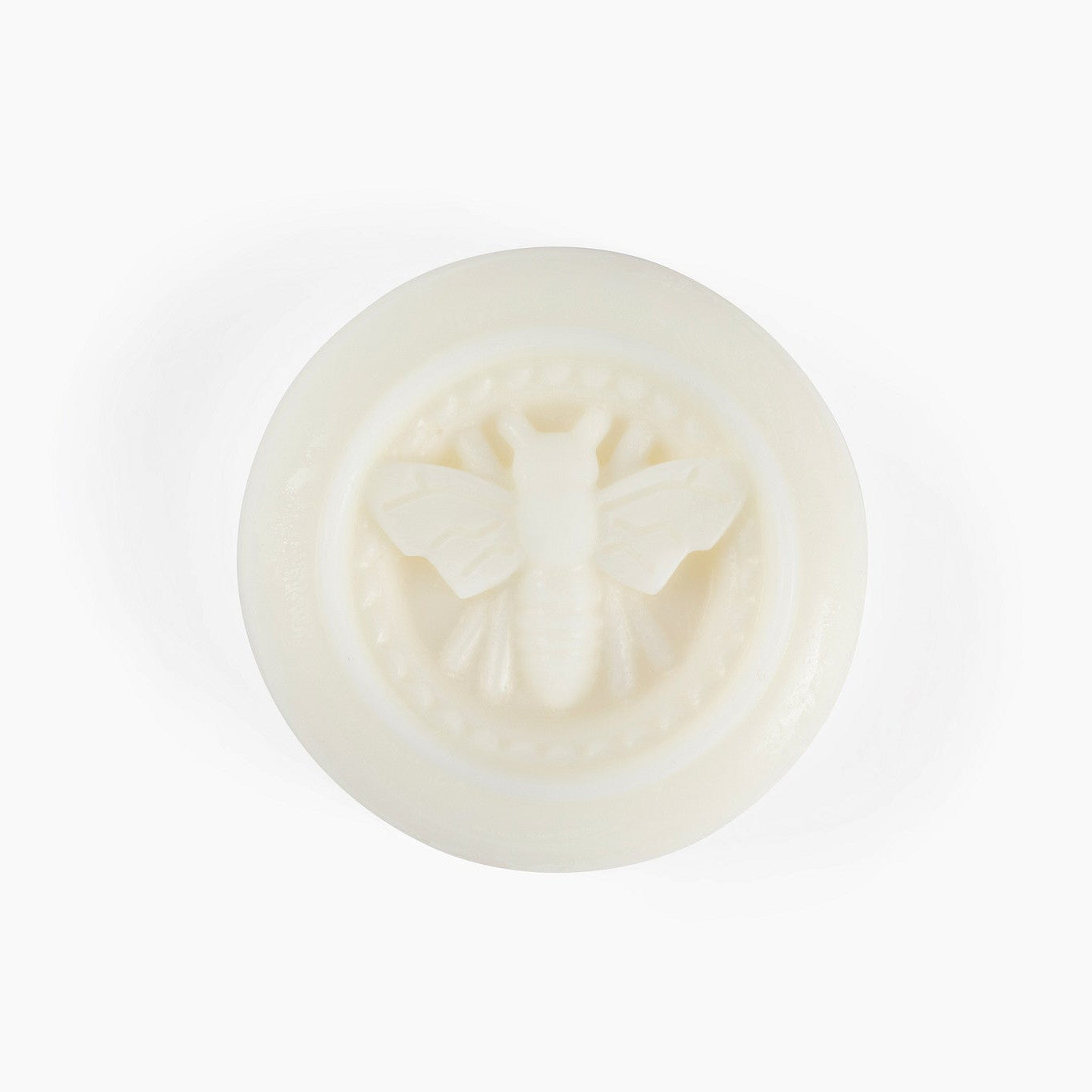 Round off white beeswax puck with a bee design on a white background