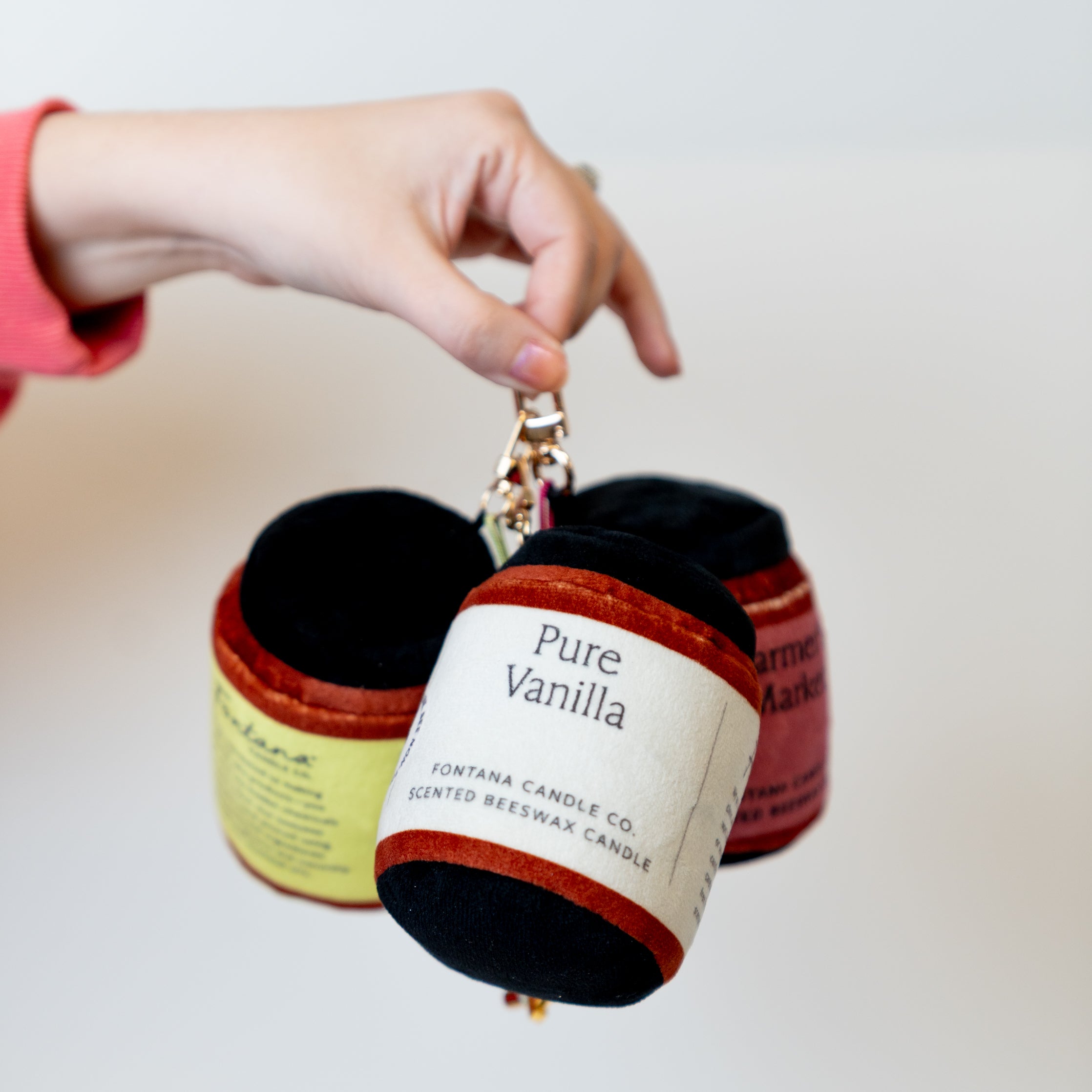 keychain of pure vanilla, lemongrass eucalyptus and farmers market being held up against a neutral background 
