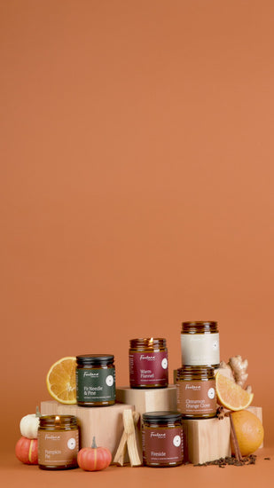 Collection of candles with pumpkins, oranges, and cinnamon sticks on a brown background