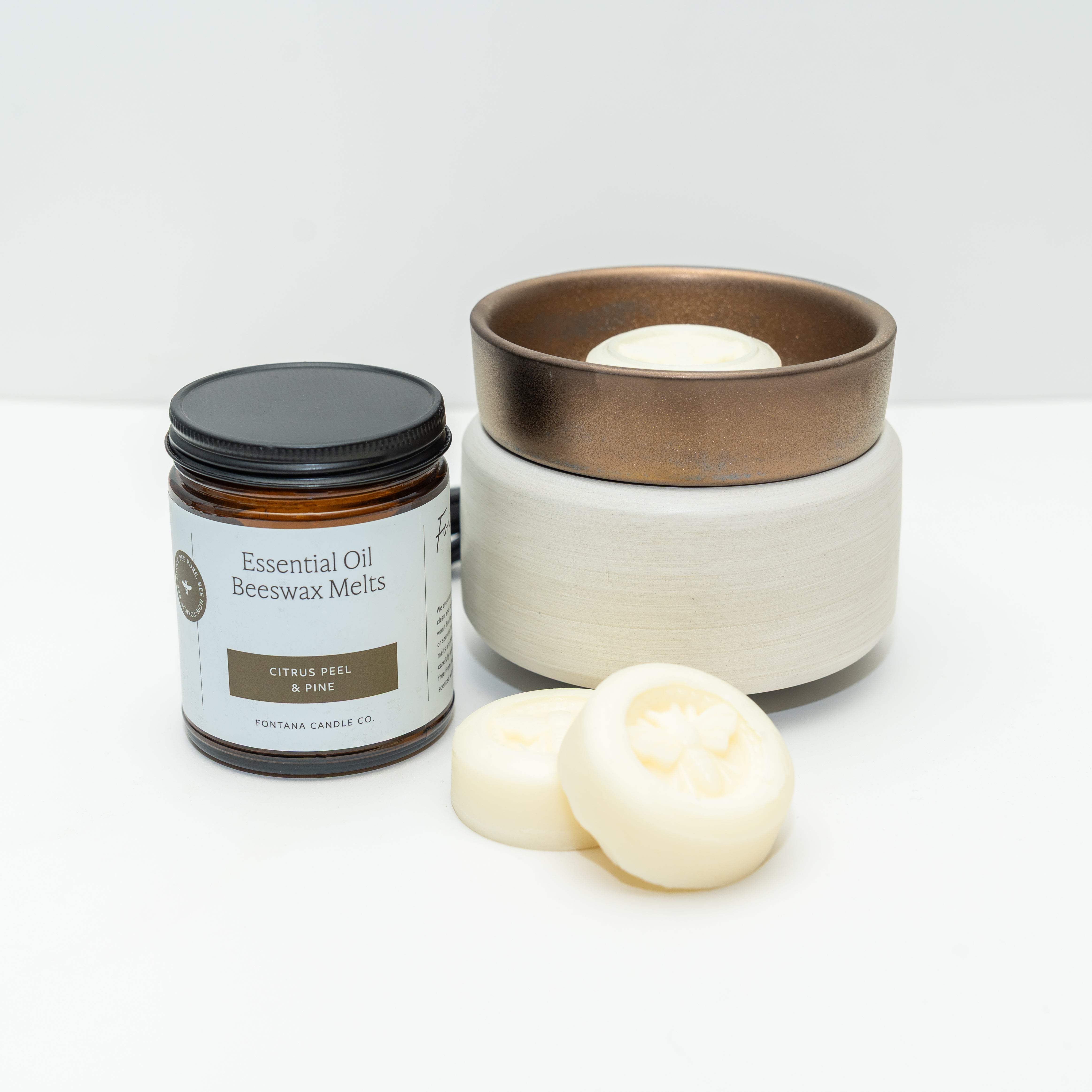 Ceramic wax warmer with a white bottom and bronze top. The picture also shows a jar of Fontana Wax Melts, on a white background.