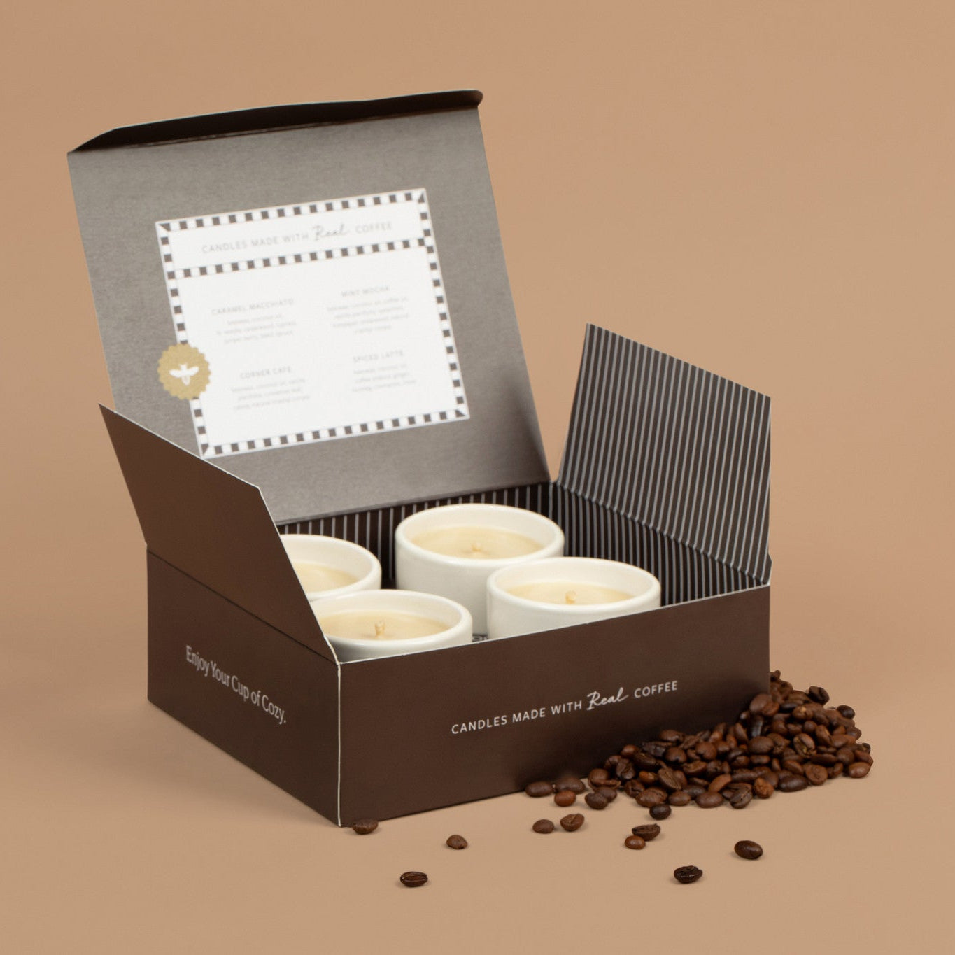 Open box containing 4 white ceramic espresso cups with on a brown background, surrounded by coffee beans.