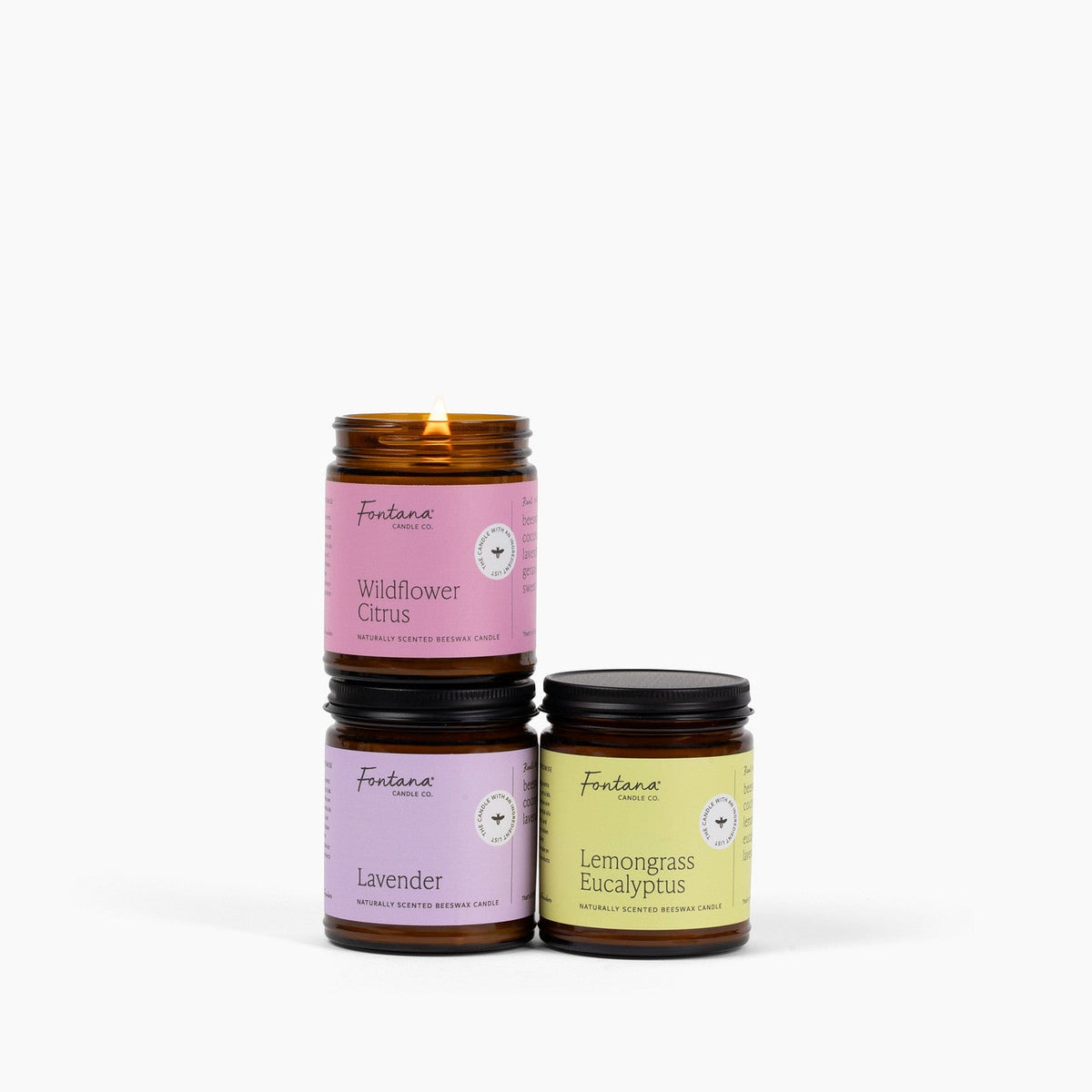 Three bright spring amber glass jar candles with different scents on a white background.