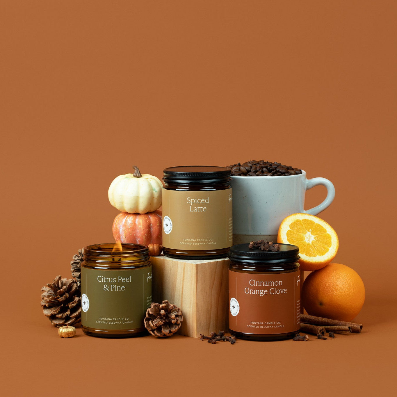 Collection of amber glass jar candles and mugs on a brown background.