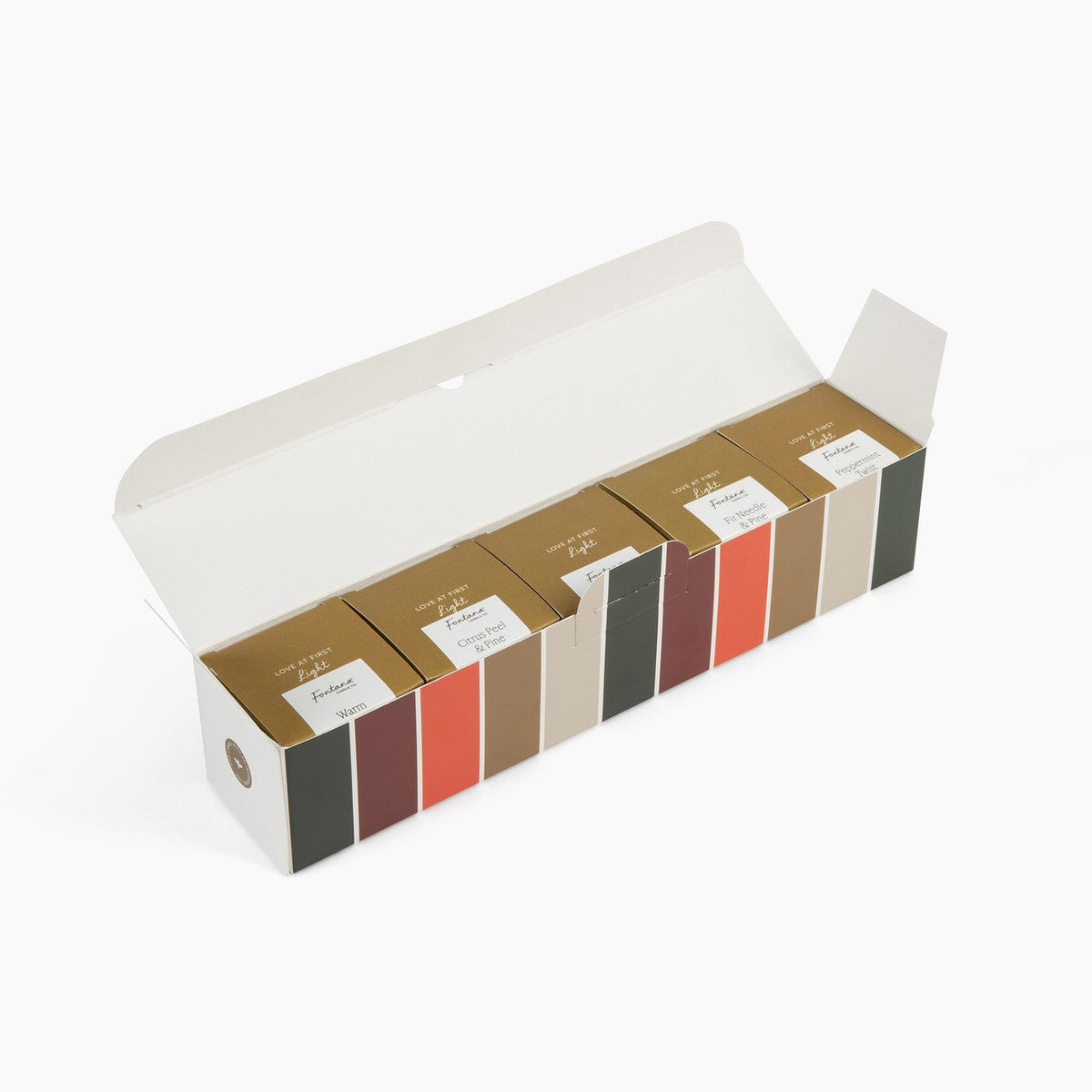 A long rectangle box featuring holiday colors that have 5 smaller internal gold boxes that hold the mini candles, in front of a white background.