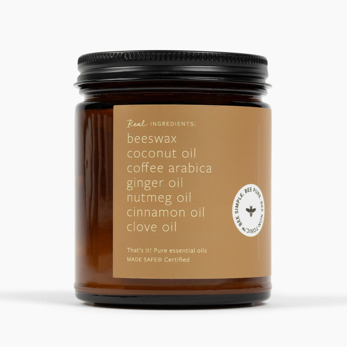 Side angle of an amber glass jar candle with a brown label and ingredients: beeswax, coconut oil, coffee arabica, ginger oil, nutmeg oil, cinnamon oil, and clove. 