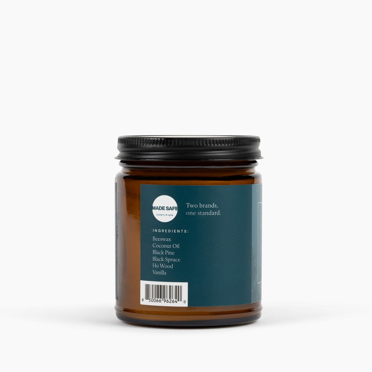 side view of an amber glass jar candle with a blue label, showing the made safe logo, and candle ingredients in front of a white background.