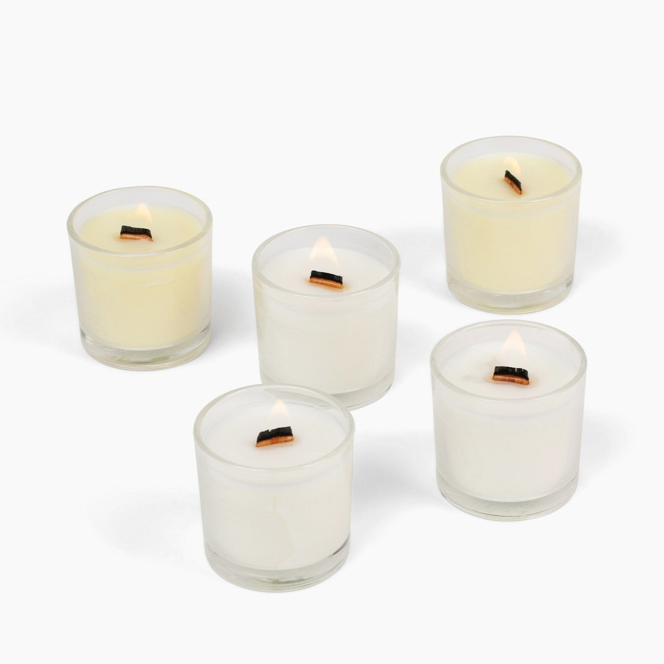 Five small glass candles with visible flames on a white background