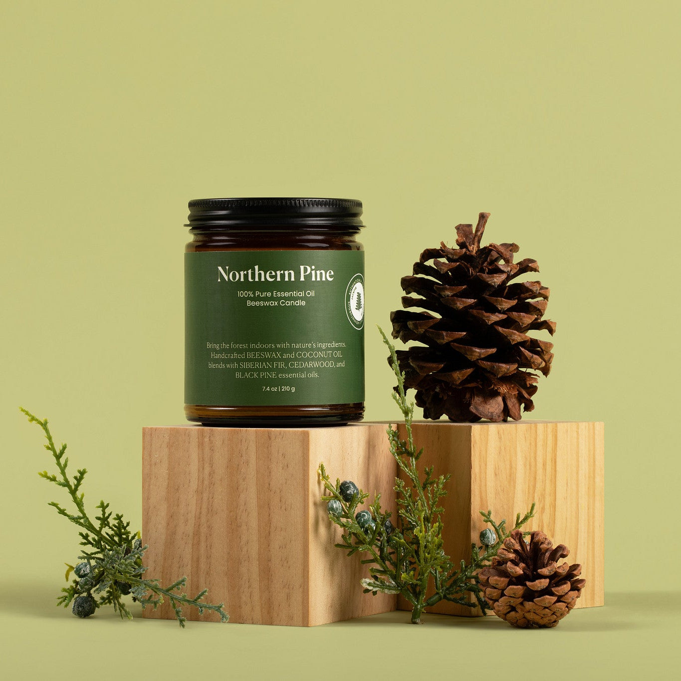 Jar of 'Northern Pine' on a wooden block with pine cones and branches against a green background