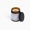 Unlit wooden wick candle with a light blue label, in front of a white background. 