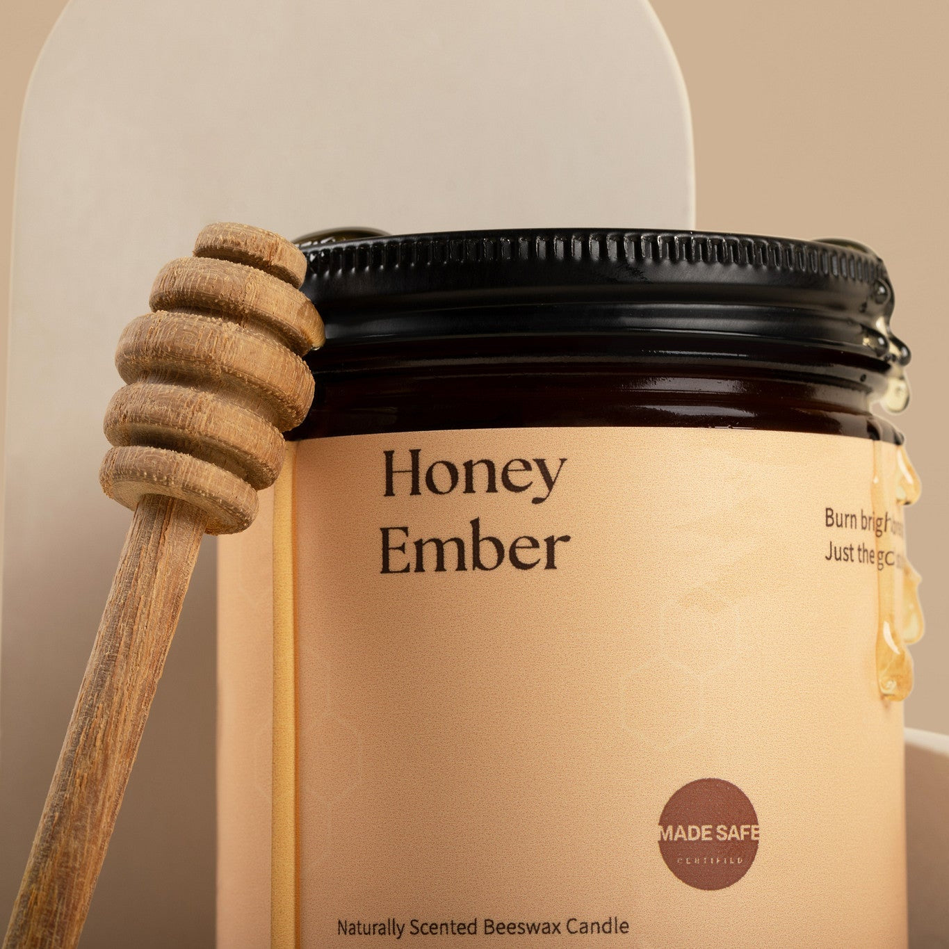 Honey Ember candle with a wooden honey dipper on a beige background