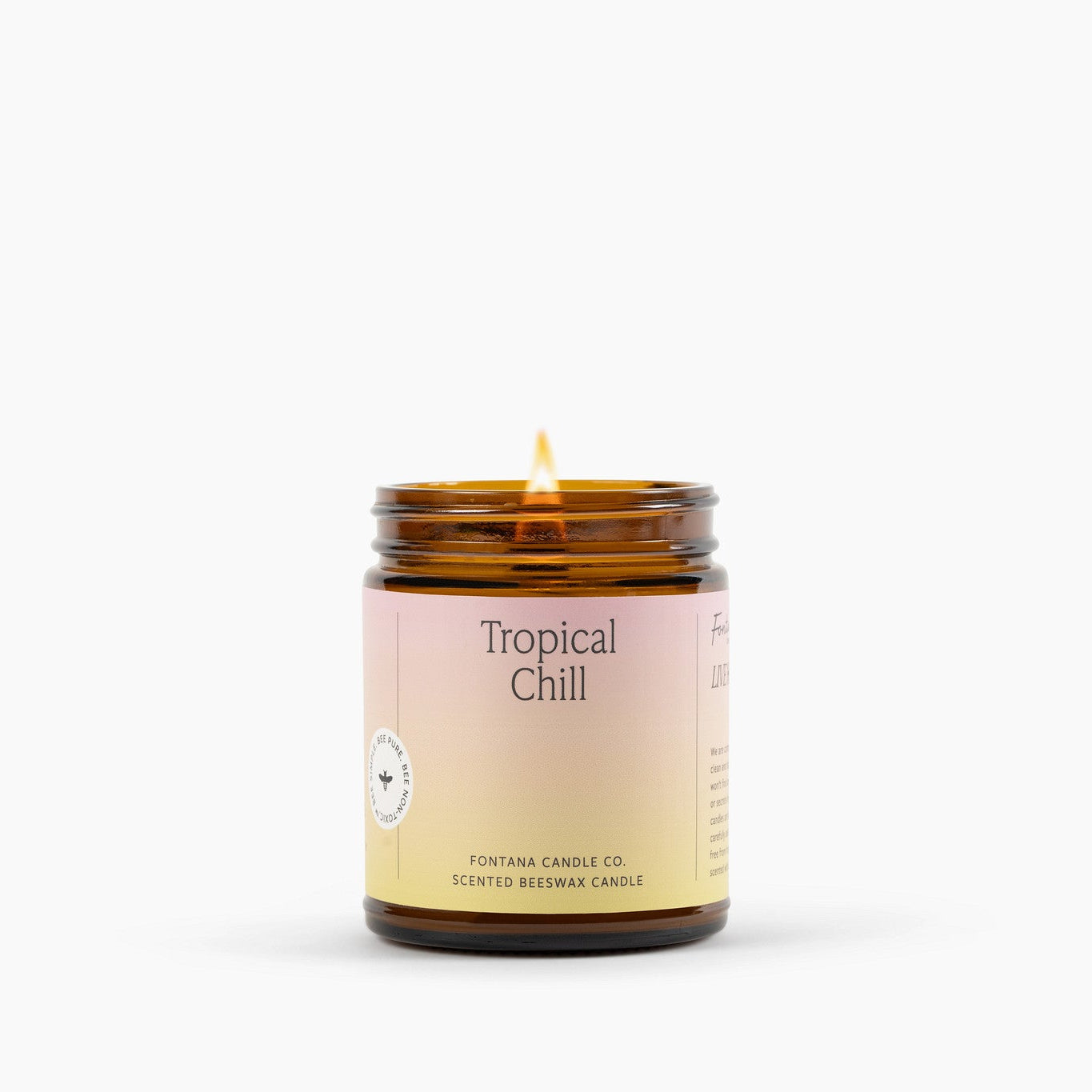 Lit amber glass jar candle with a bright pink and yellow label in front of a white background.