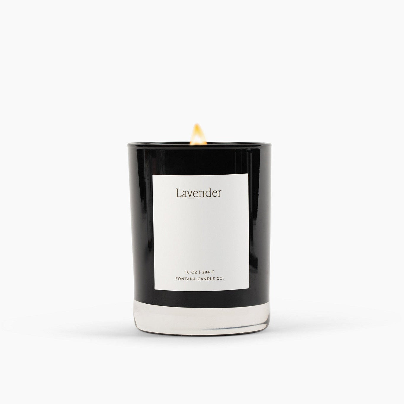 Lit black glass candle with a white label on a white background. 