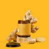 Amber glass Jar  candle of 'Ginger Chai' with ginger roots on a yellow background