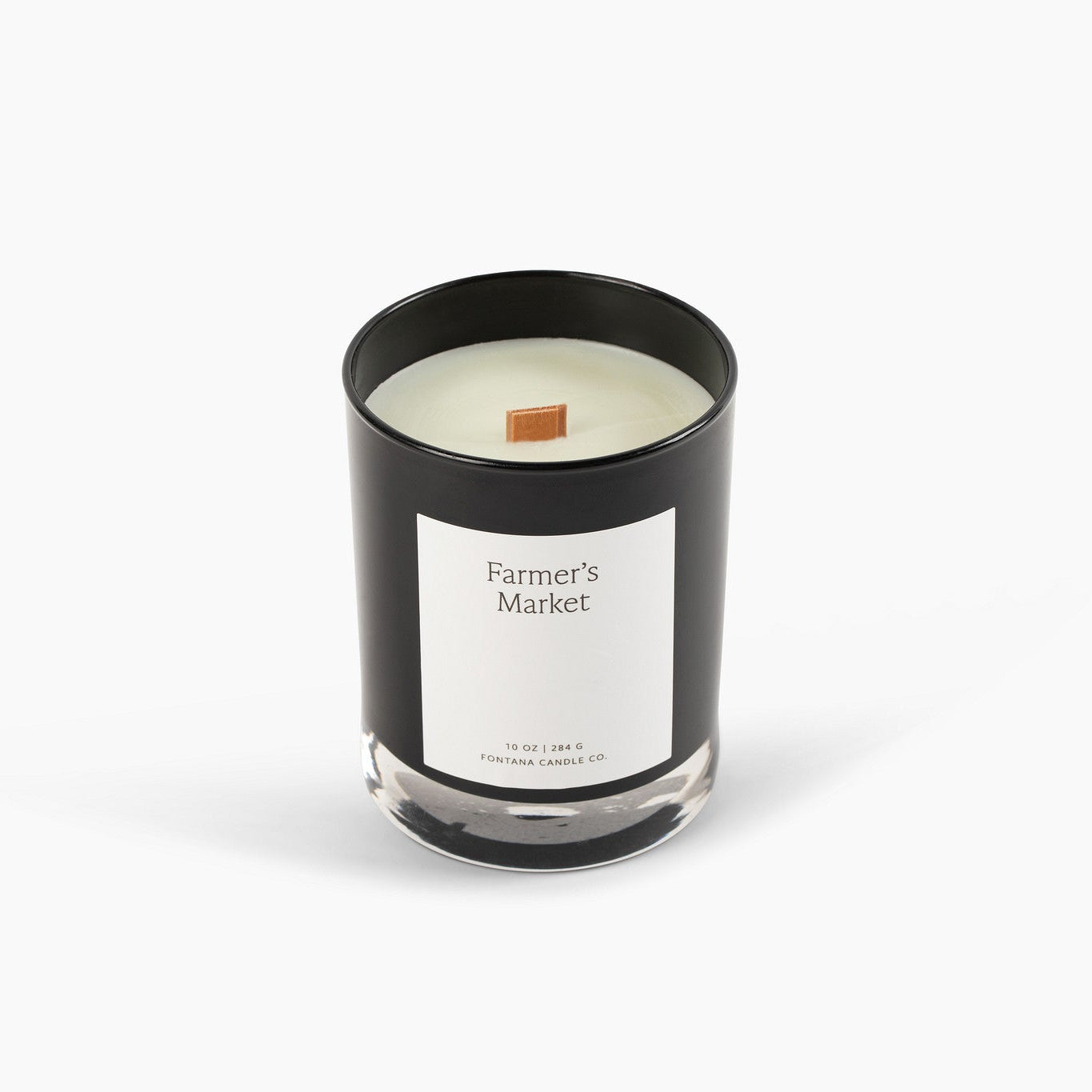 Black glass candle with a wooden wick and 'Farmer's Market' label on a white background