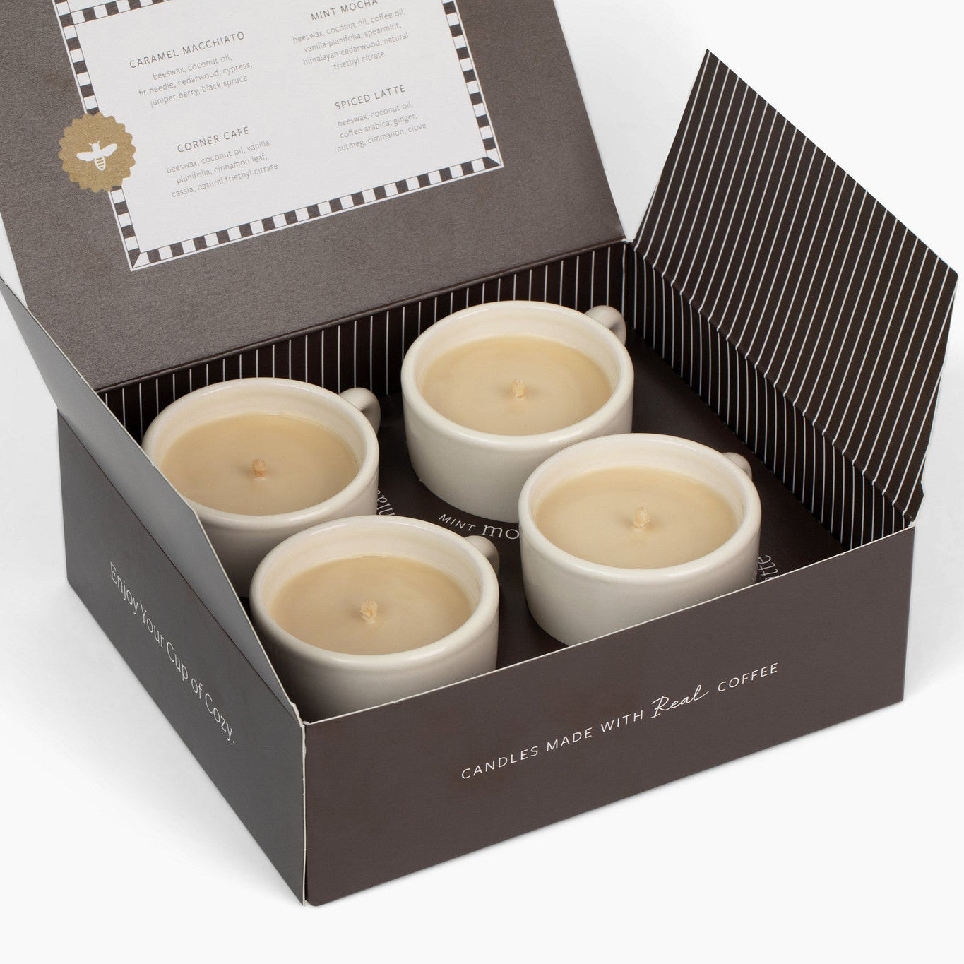 Four coffee-themed candles in a decorative box with a label on a white background