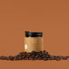 Amber glass jar of Spiced Latte with coffee beans on a brown background.
