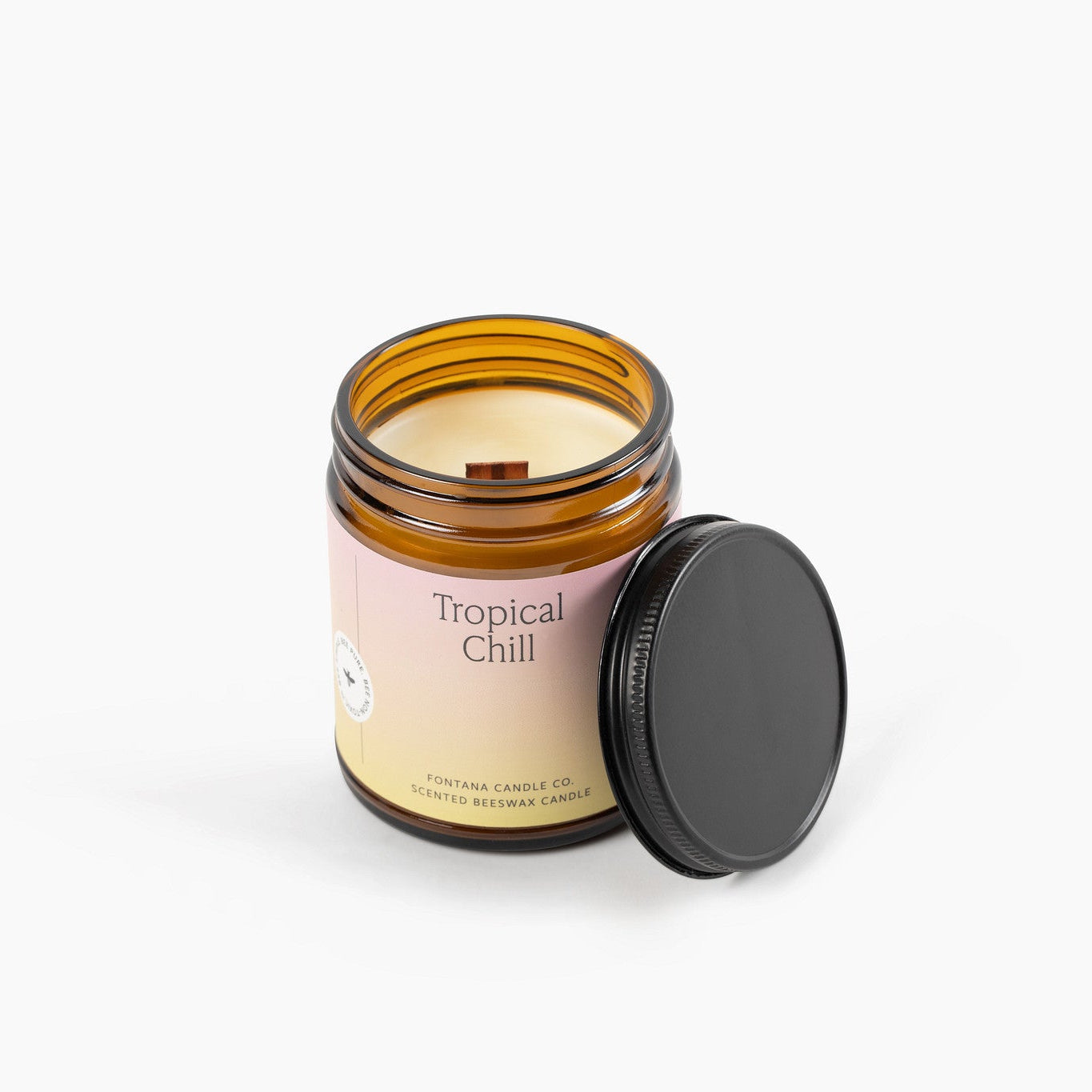 Tropical Chill amber glass jar candle with a wooden wick a black lid on a white background.
