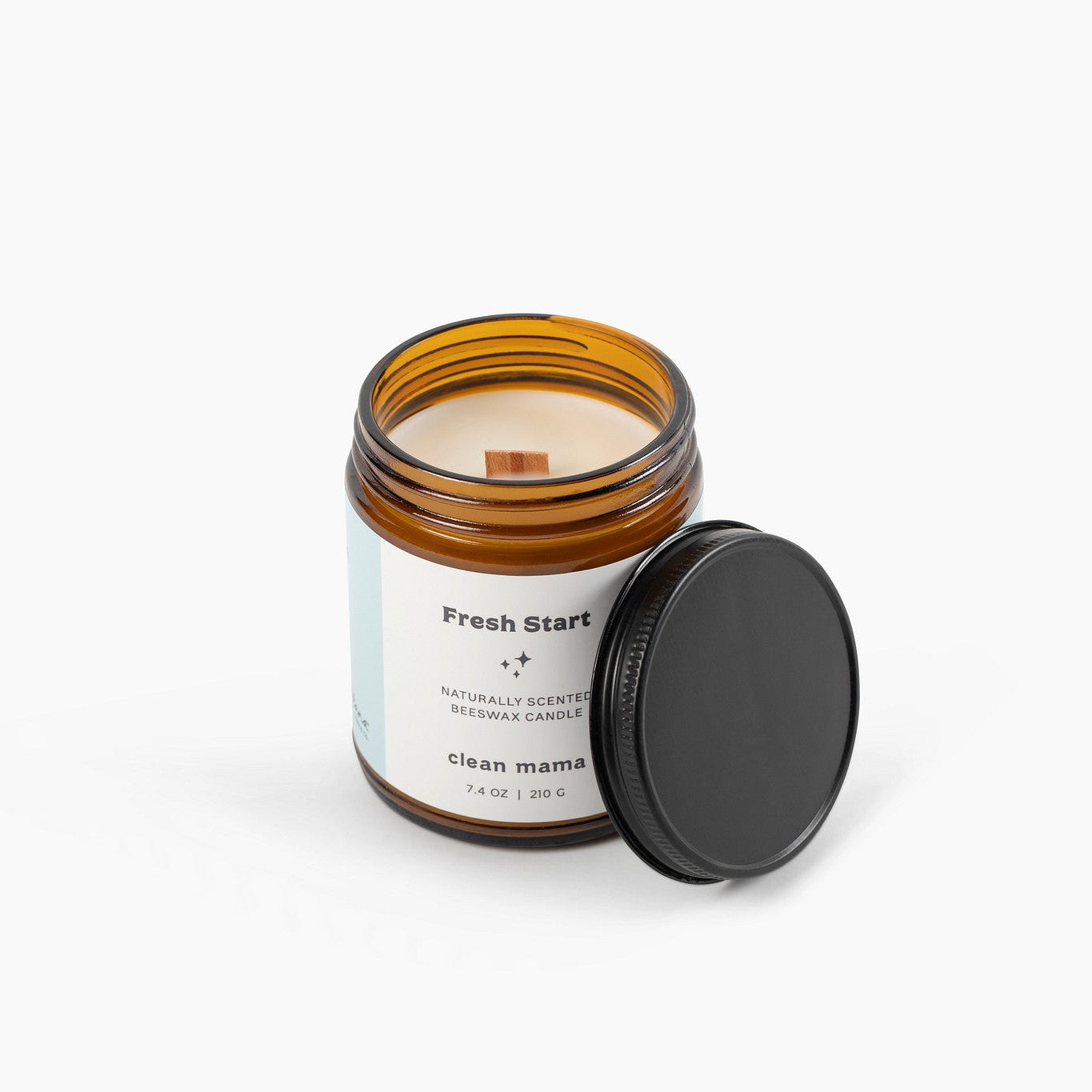 Amber glass jar candle with a wooden wick in front of a white background.