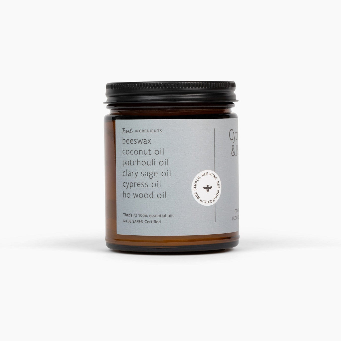 Side view of an amber glass jar candle, with a black lid and a light blue label. 