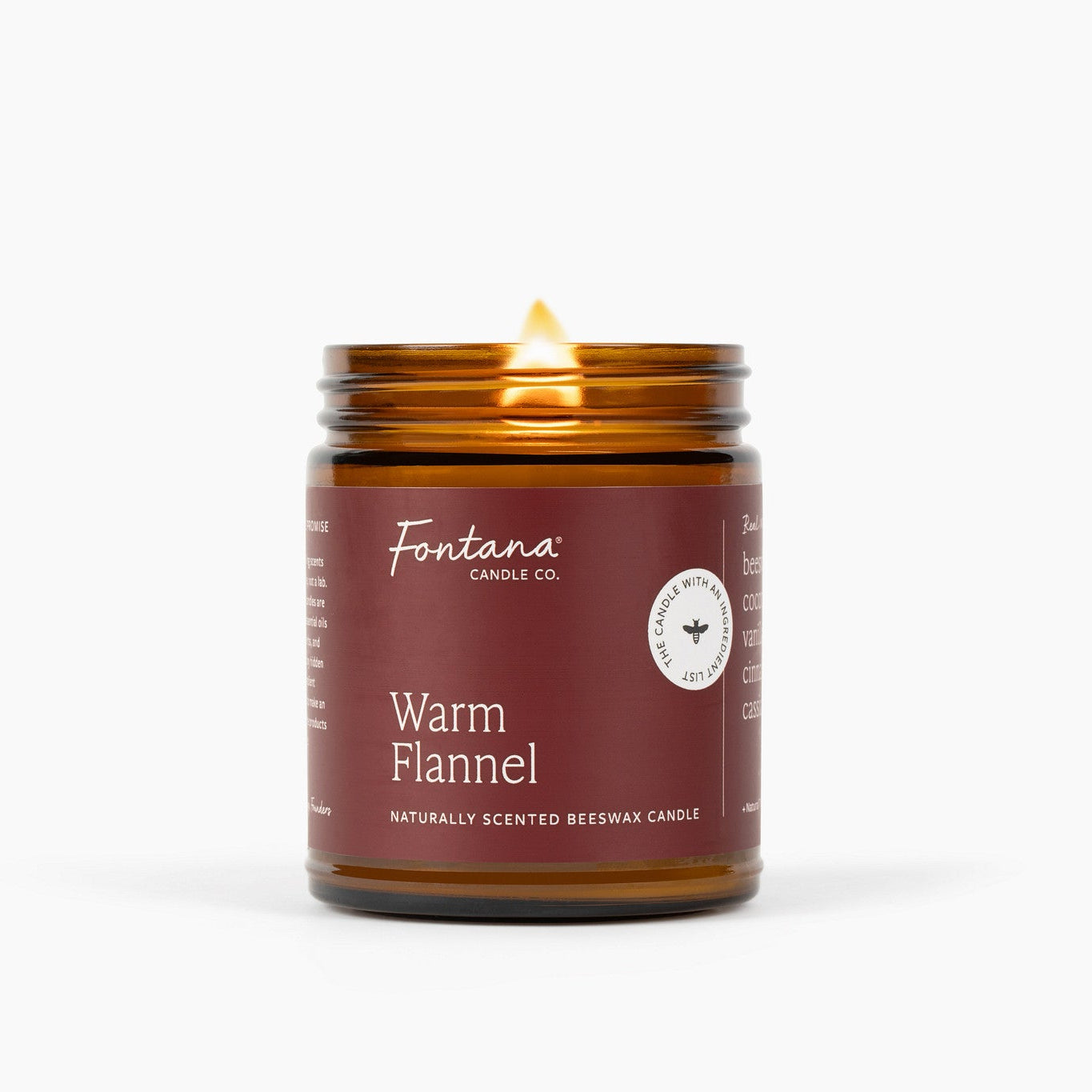 A lit amber glass jar candle with a dark reddish-brown label reading Fontana Candle Co. and Warm Flannel, shown on a clean white background.