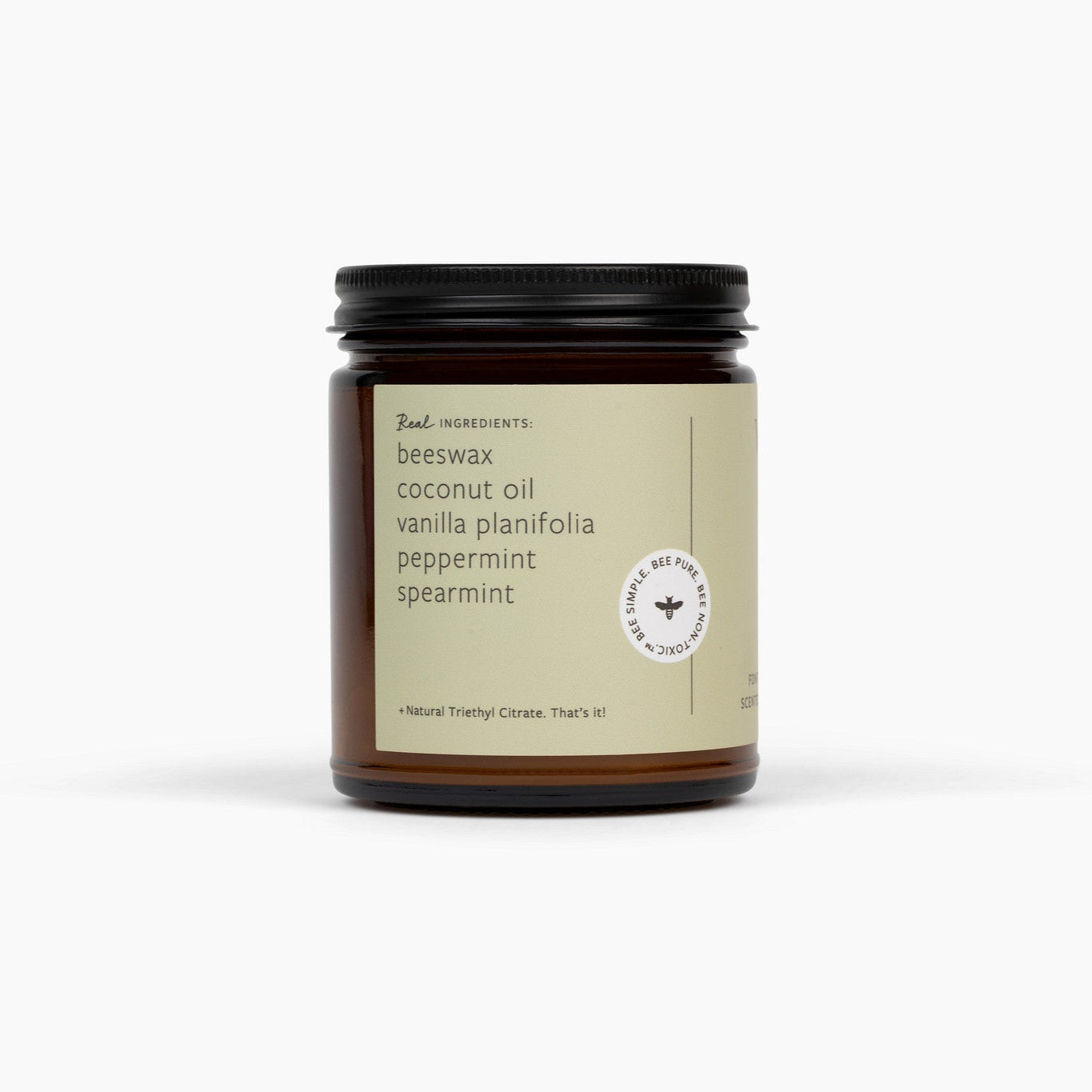Side view of an amber glass jar candle, with a black lid on top, and a light green label. Candle is in front of a white background.