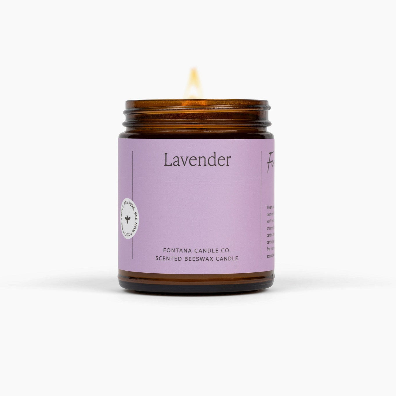 Lit amber glass jar candle with a purple label, on a white background.